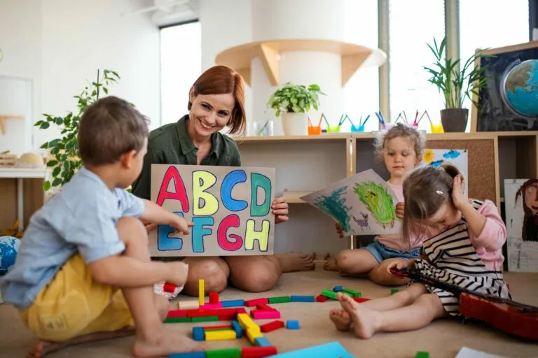 a woman and children sitting on the floor with a sign emphasing early childhood intervention